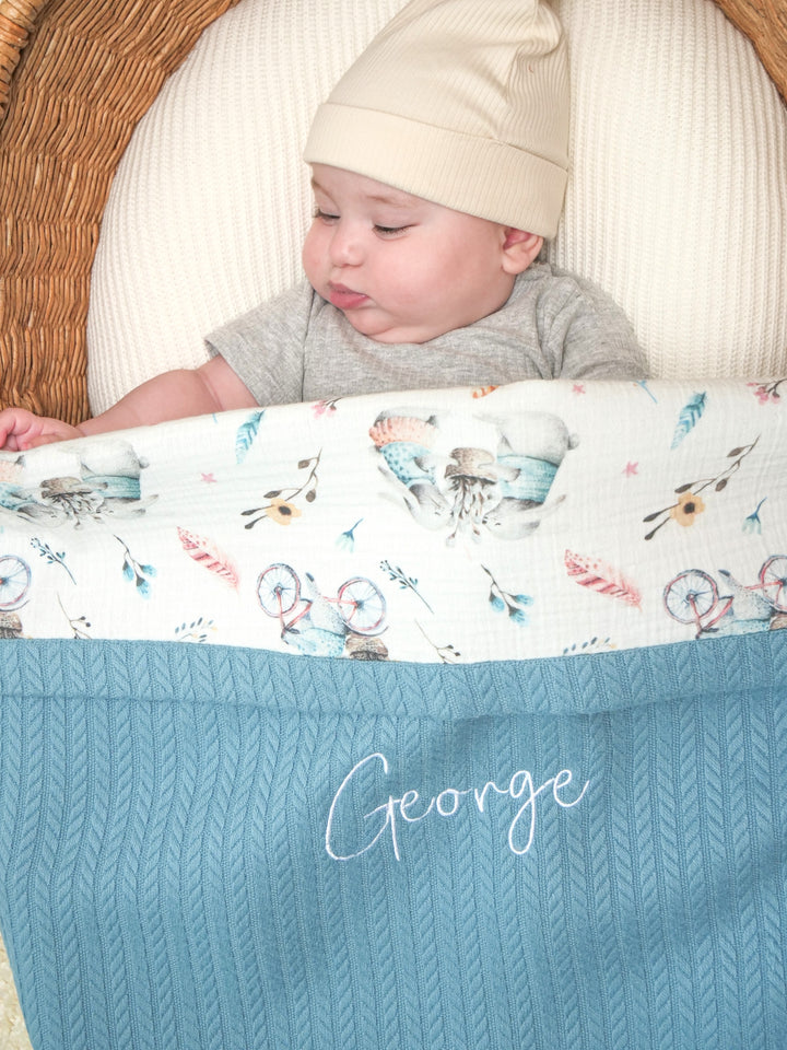 Mouliss close-up of embroidered name on personalized blue cable knit baby blanket with bicycle muslin