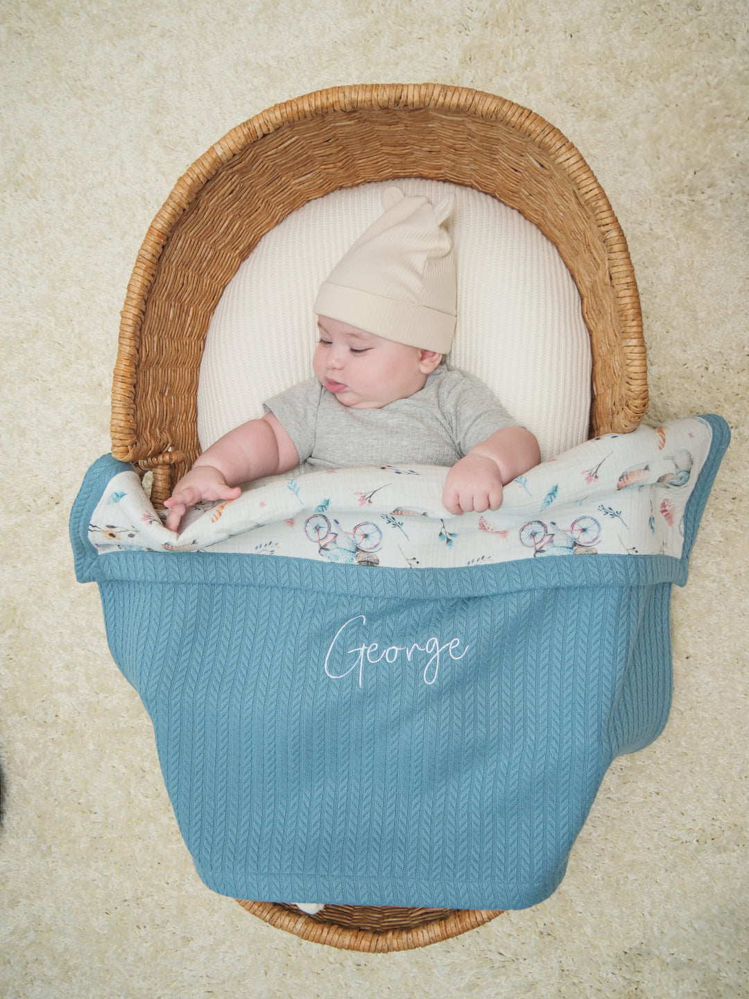 Mouliss baby in basket with personalized blue cable knit baby blanket, bicycle muslin, embroidered name
