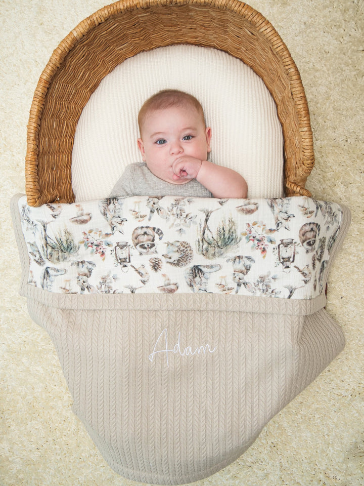 Personalized beige waffle baby blanket with woodland animal muslin and embroidered name, baby in basket