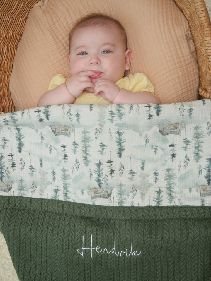 Mouliss close-up of embroidered name on personalized green cable knit baby blanket with pine tree muslin