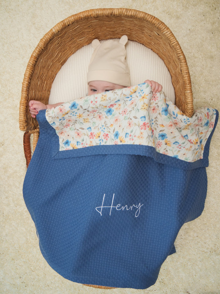 Mouliss baby in basket with personalized navy waffle baby blanket, floral muslin, embroidered name