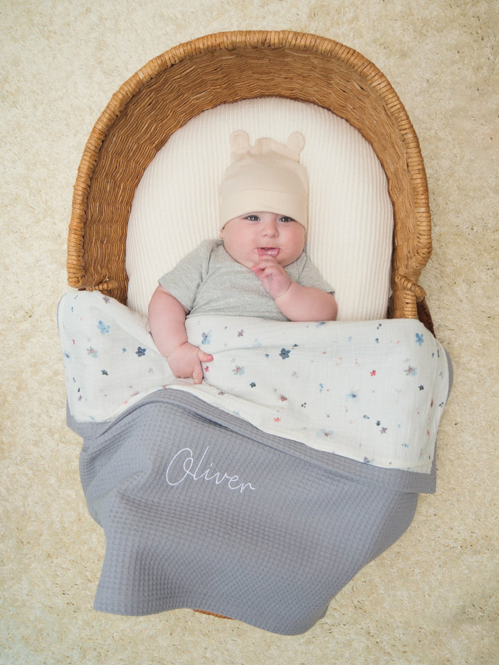 Mouliss personalized grey baby blanket with floral muslin, embroidered name, shown in basket