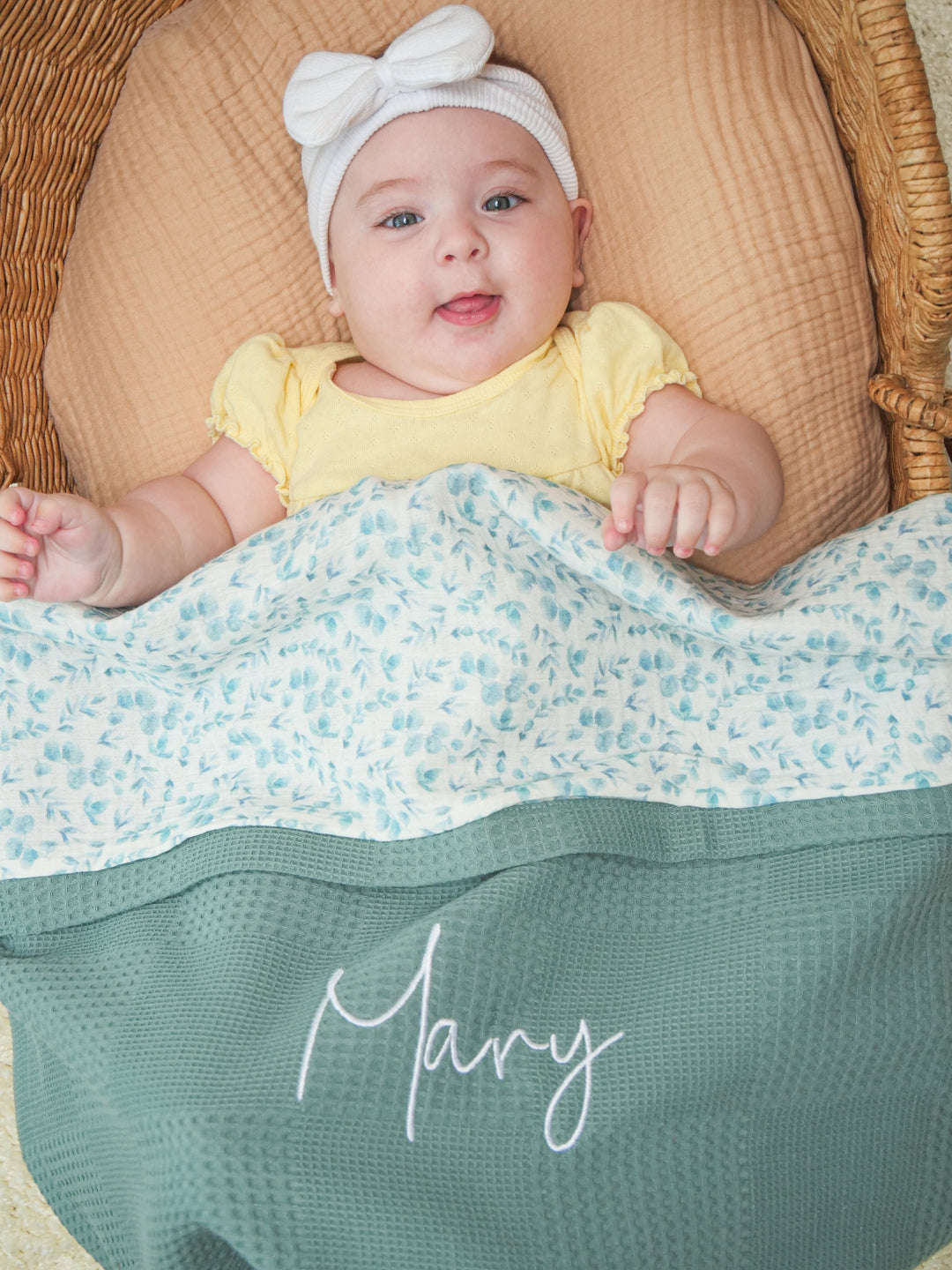 Mouliss close-up of embroidered name on personalized sage green baby blanket with floral muslin