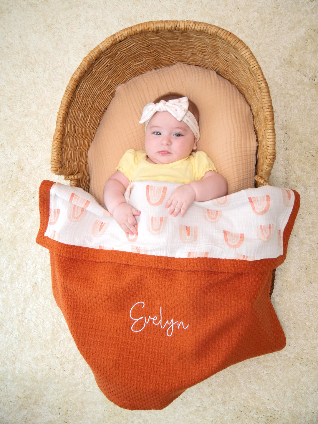 Mouliss baby in basket with personalized rust waffle baby blanket, rainbow muslin, embroidered name