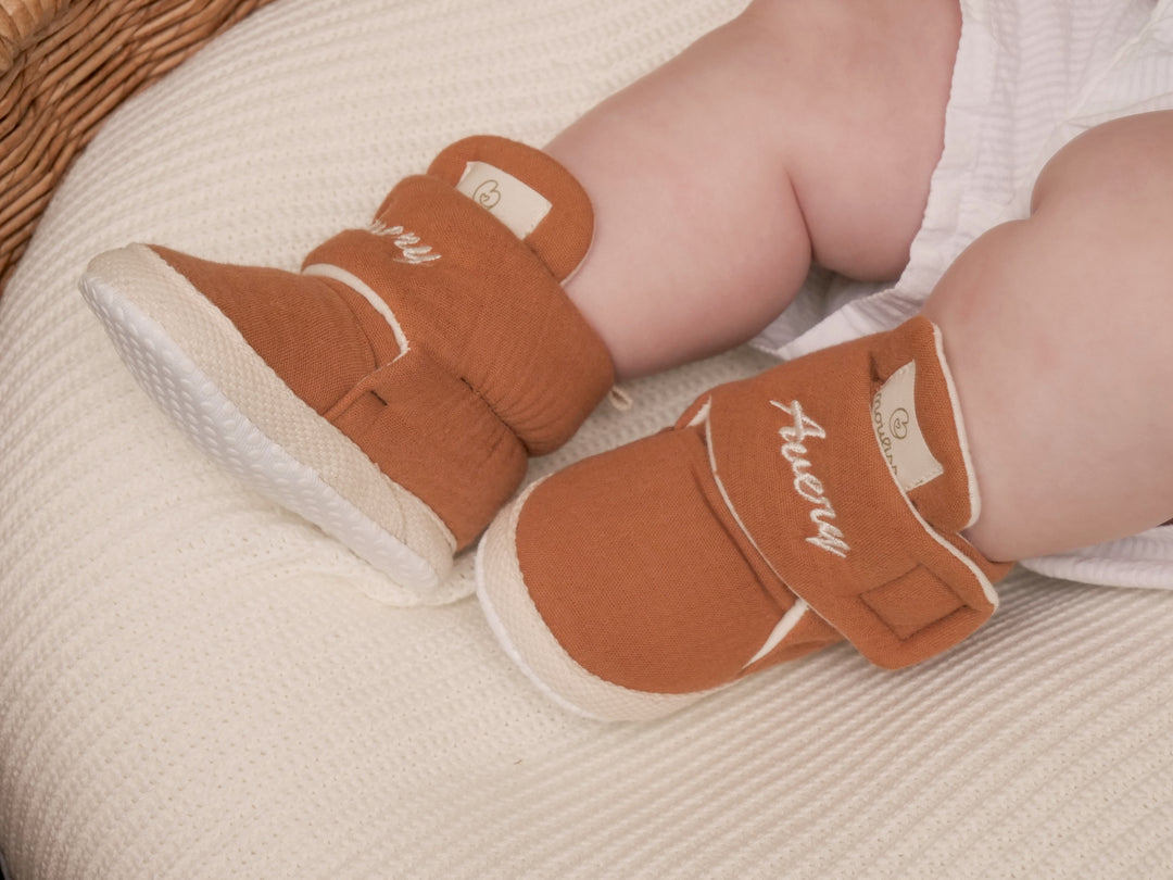 Mouliss baby wearing personalized terracotta baby booties with embroidered name, in basket