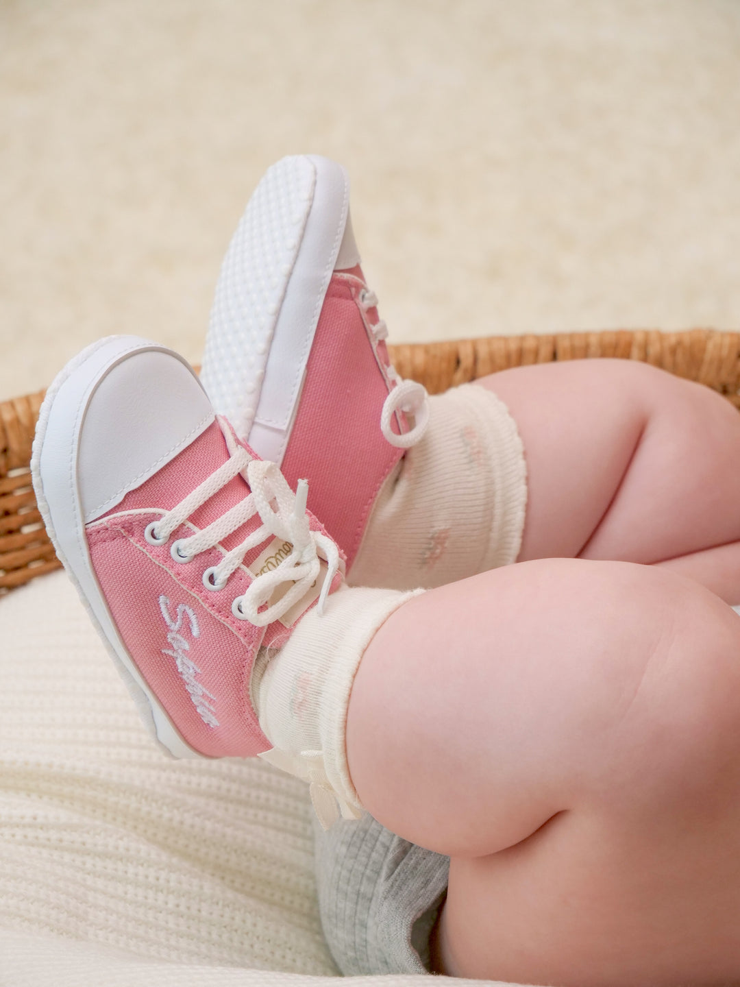 Mouliss baby wearing personalized pink canvas baby shoes with embroidered name, in basket