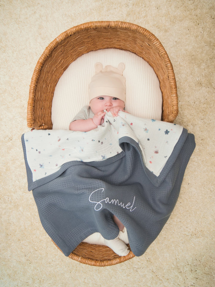 Mouliss baby in basket with personalized grey waffle baby blanket, floral muslin, embroidered name