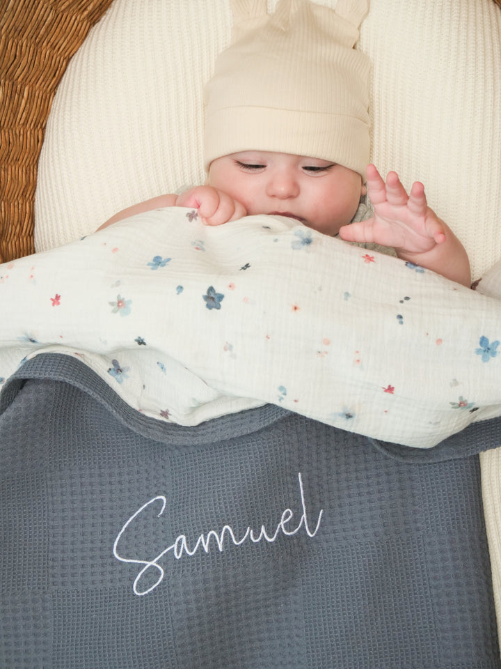 Mouliss close-up of embroidered name on personalized grey waffle baby blanket with floral muslin