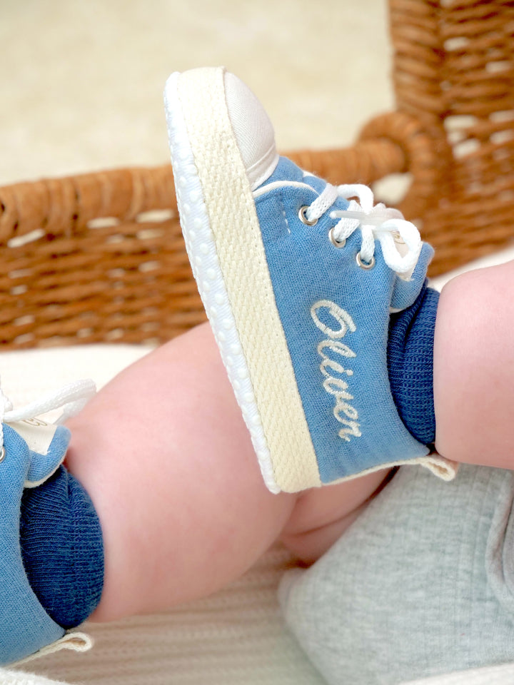 Mouliss personalized denim blue baby shoes with embroidered name, side view in basket