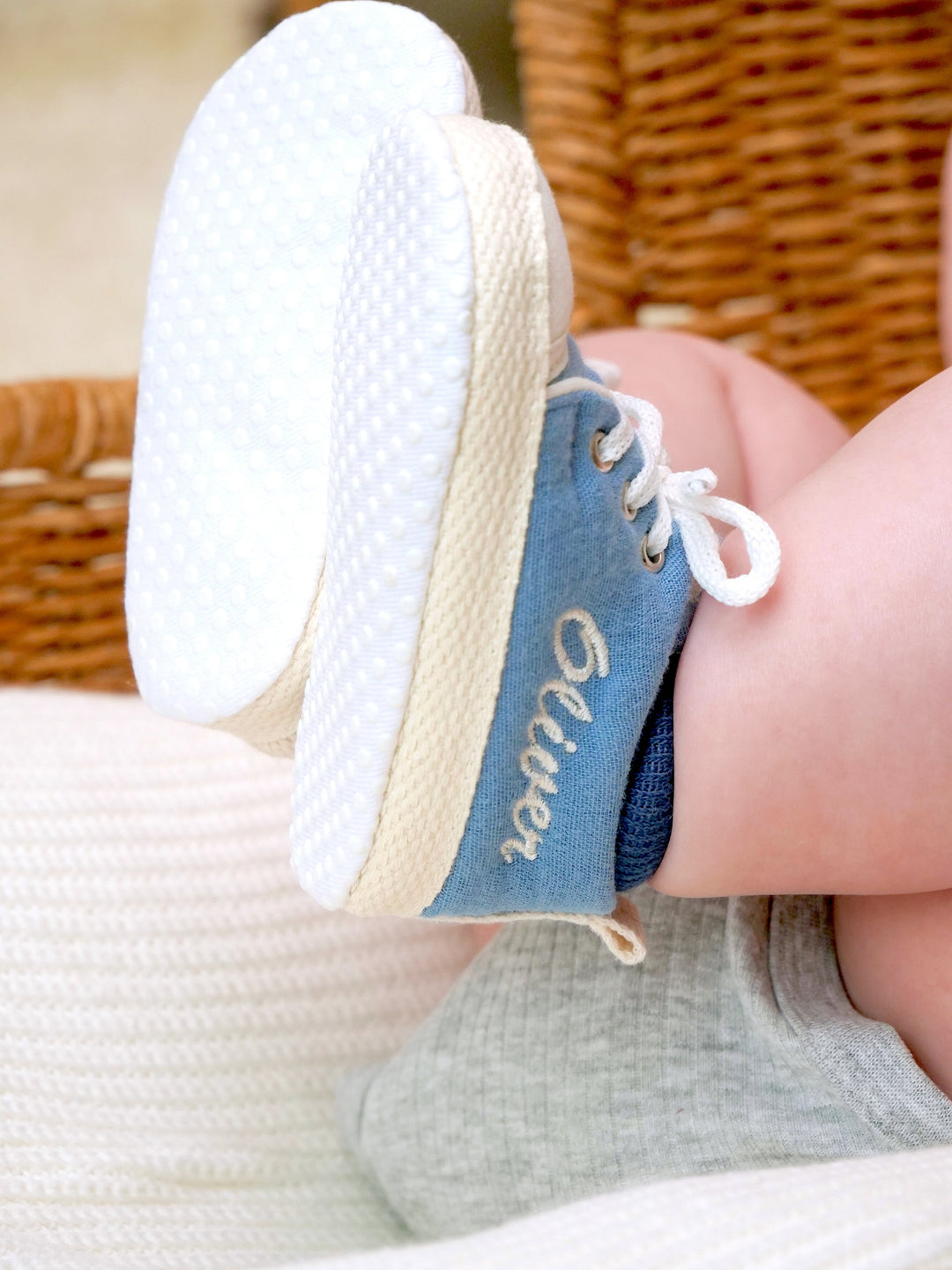 Mouliss close-up of personalized denim blue baby shoes with embroidered name in basket