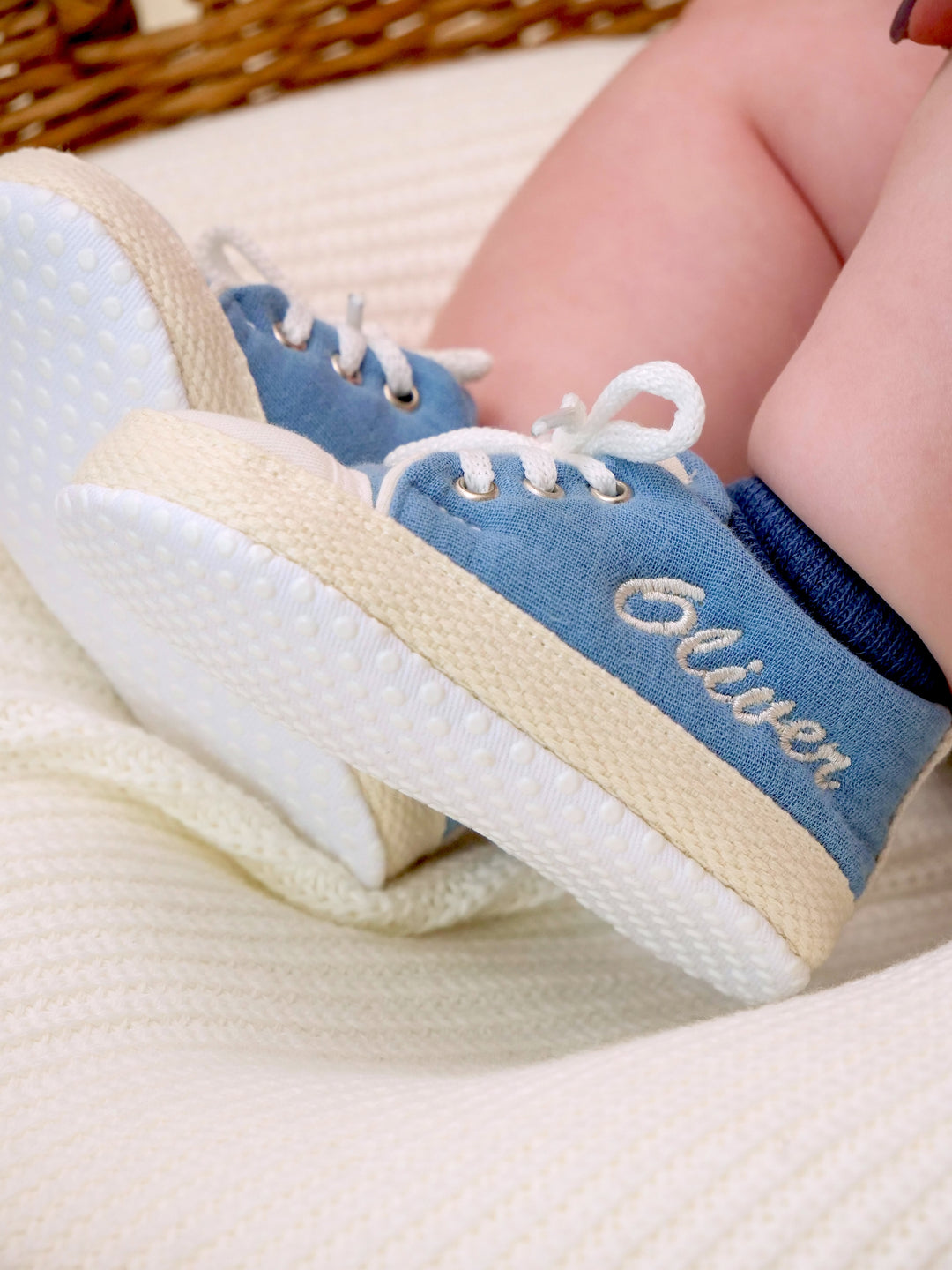 Mouliss baby wearing personalized denim blue baby shoes with embroidered name, in basket
