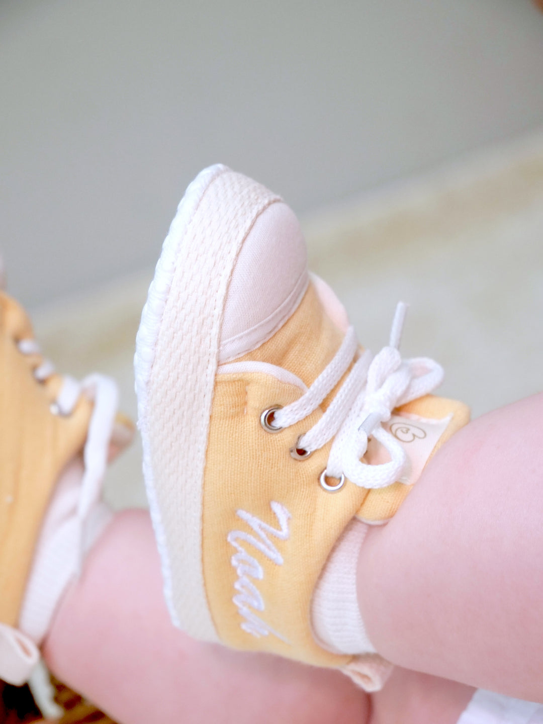 Mouliss baby wearing personalized honey yellow baby shoes with embroidered name, in basket