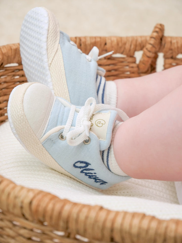Mouliss baby wearing personalized blue baby shoes with embroidered name, in basket