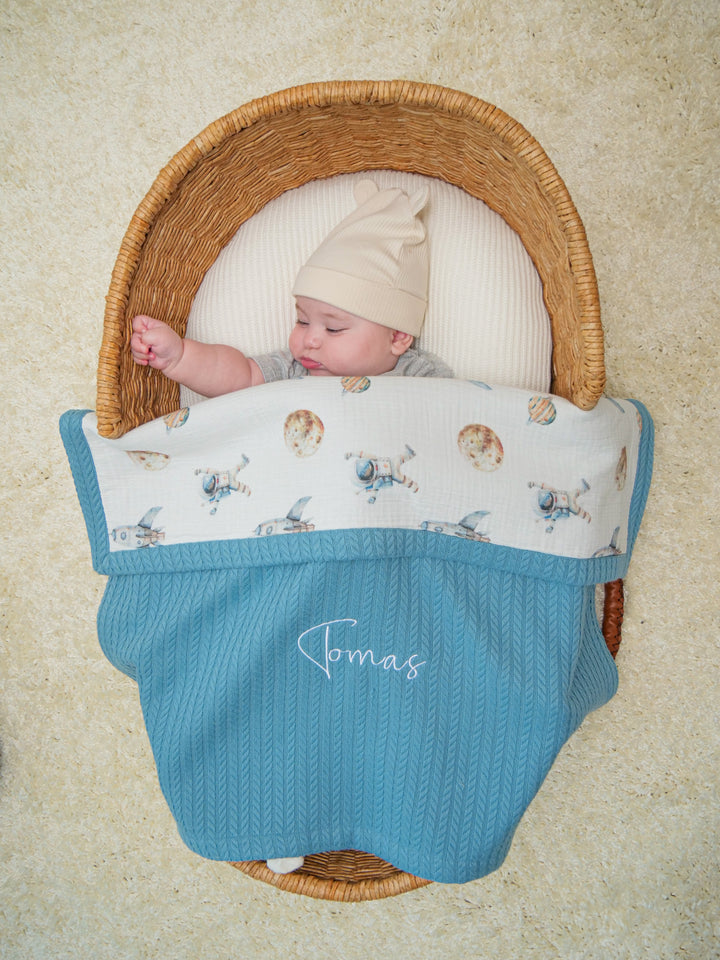 Mouliss baby in basket with personalized blue waffle baby blanket, astronaut muslin, embroidered name