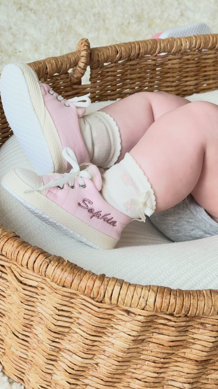 Mouliss personalized pink baby shoes with embroidered name, shown on baby in basket