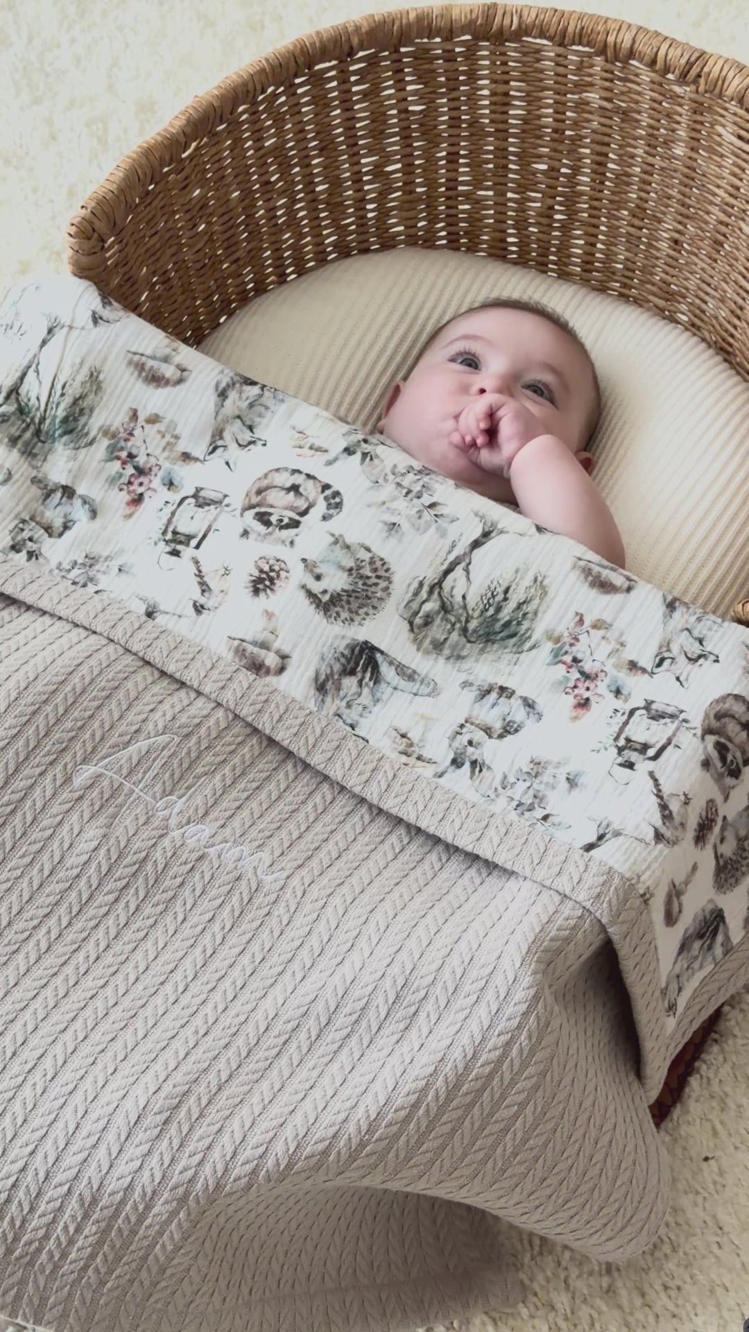 Personalized beige baby blanket with woodland muslin and embroidered name shown in woven basket